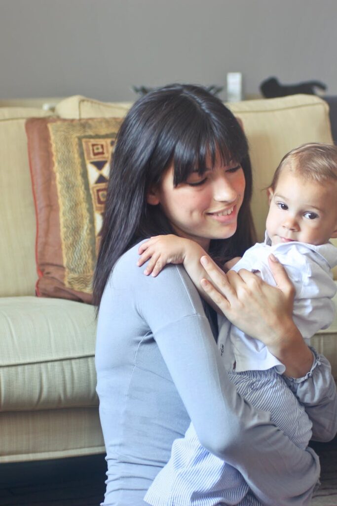 A mother lovingly embraces her baby indoors on a comfortable sofa capturing warmth and togetherness.